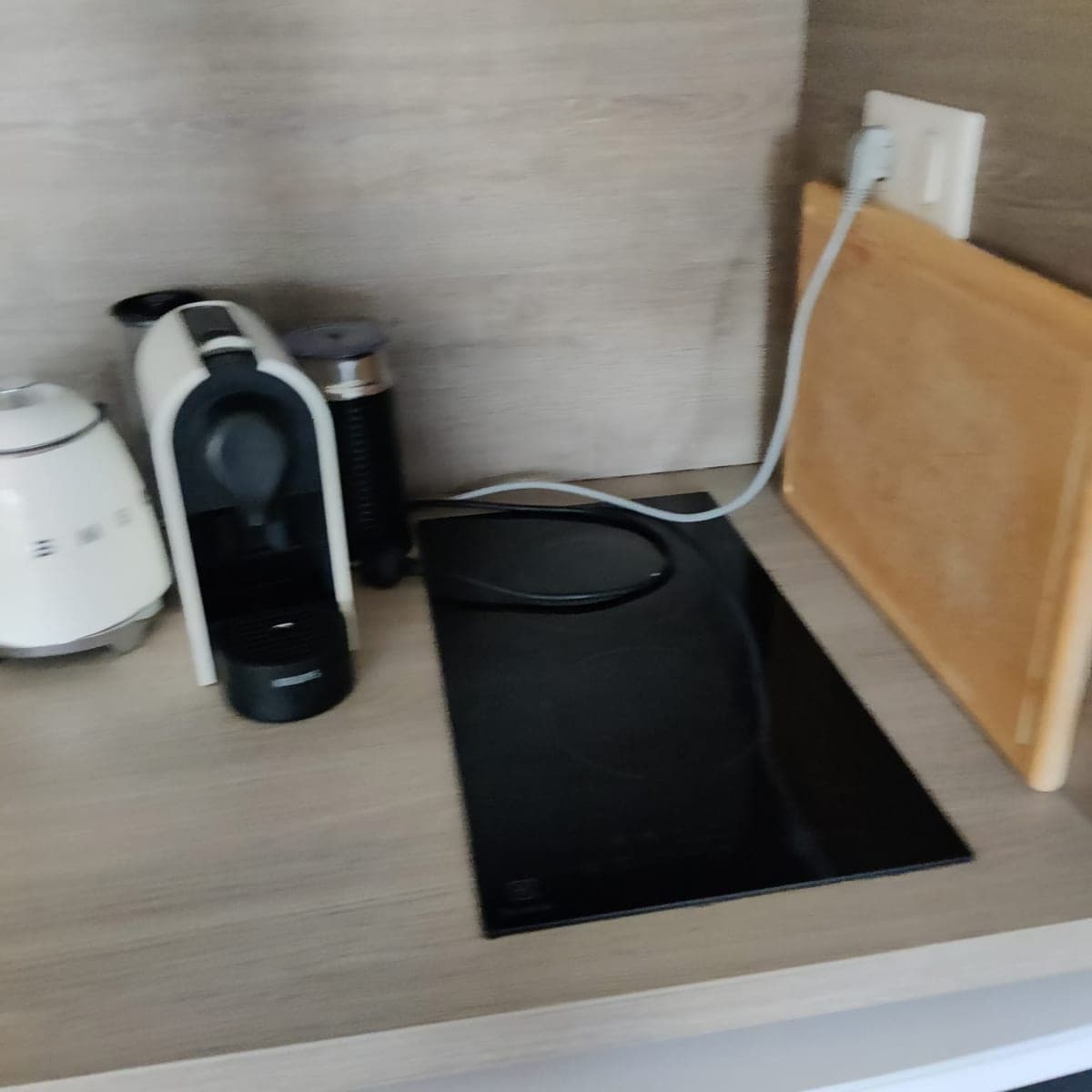 Plan de travail bois clair net, plaque de cuisson noire dégagée, bouilloire et machine à café