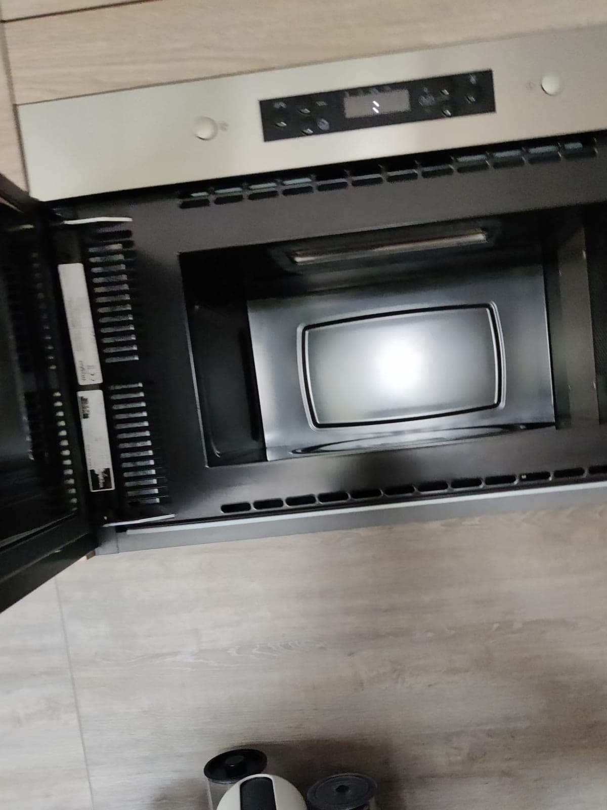 Four micro-ondes encastré ouvert, intérieur noir propre, sous un meuble en inox