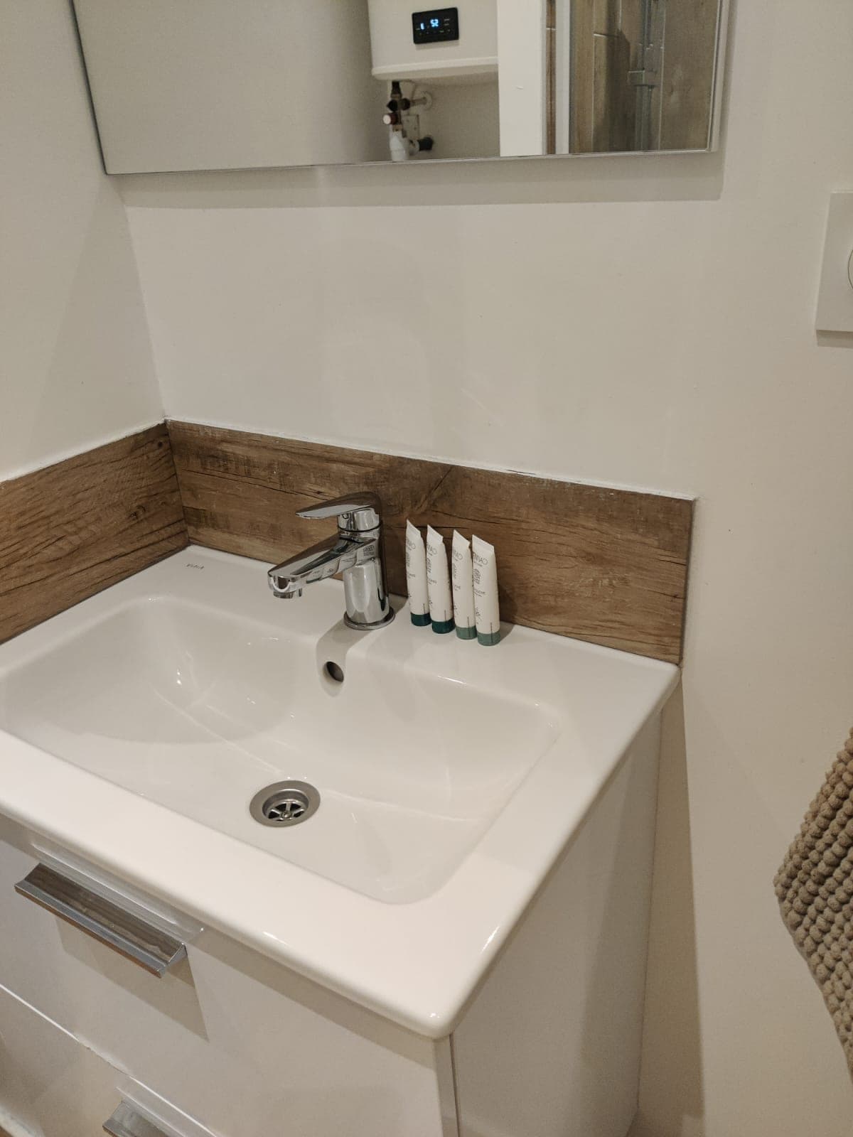 Lavabo blanc sur meuble blanc, robinet chromé et crédence imitation bois, propres