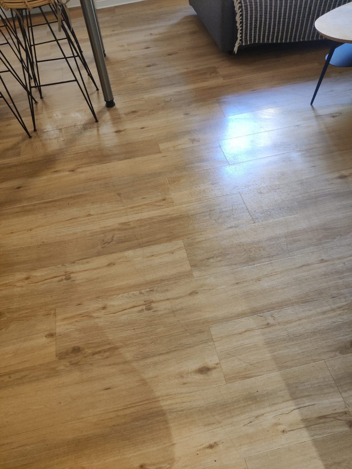 Parquet clair brillant, avec reflets de lumière, devant une table à pieds métalliques noirs