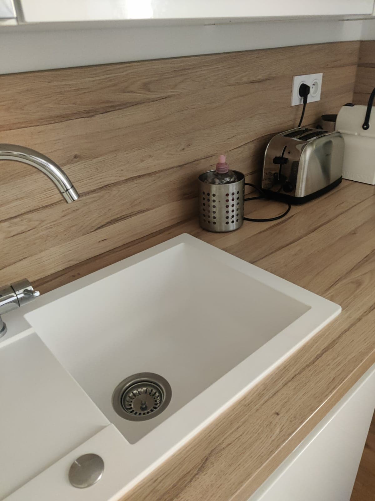 Évier blanc à égouttoir dans un plan de travail bois, sur crédence en bois, propre et dégagé